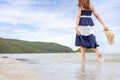 Woman barefoot hold hat and walking on summer along wave of sea water and sand on the beach Royalty Free Stock Photo