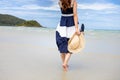 Woman barefoot hold hat and walking on summer along wave of sea water and sand on the beach Royalty Free Stock Photo