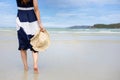 Woman barefoot hold hat and walking on summer along wave of sea water and sand on the beach Royalty Free Stock Photo