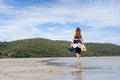 Woman barefoot hold hat and walking on summer along wave of sea water and sand on the beach Royalty Free Stock Photo