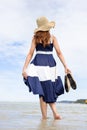 Woman barefoot hold her shoes walking on summer along wave of sea water and sand on the beach Royalty Free Stock Photo