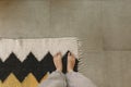 Woman barefoot standing on modern rug in comfortable stylish home, top view. Feet on woolen rug