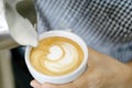 Woman barista pouring stream milk for making latte art coffee with heart shape in white cup, selective and soft focus Royalty Free Stock Photo