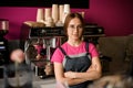 woman barista stands with her arms crossed on her chest and professional coffee machine in the background