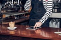 Woman barista take order by mobile and tablet,asia female waitress using digital device in coffee shop business at counter bar in