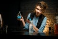 Woman bartender carefully pours drink from jigger into glass of cold water