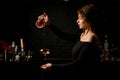 Woman bartender in dark bar masterfully pours cocktail into wineglass.