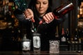 Woman bartender gently pours drink from bottle to glass with ice.