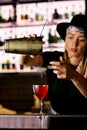 Woman bartender pouring out fresh delicious cocktail from steel shaker through sieve on steel bar counter Royalty Free Stock Photo