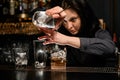 Woman bartender very carefully pours drink from one glass to another.