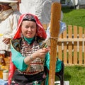 A woman in Bashkir clothes is sitting and spinning wool. Traditional national holiday Sabantuy in the city park