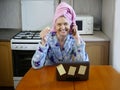 Woman in bath towel on her head and wearing bathrobe working with laptop and documents in kitchen at home, woman accountant Royalty Free Stock Photo