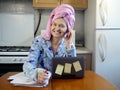 Woman in bath towel on her head and wearing bathrobe working with laptop and documents in kitchen at home, woman accountant Royalty Free Stock Photo