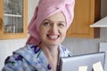 Woman in bath towel on her head and wearing bathrobe working with laptop and documents in kitchen at home, woman accountant Royalty Free Stock Photo