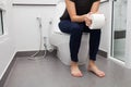 Woman in bath towel sitting on toilet bowl