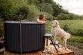 Woman bathing in hot tube, while resting with her dog on nature Royalty Free Stock Photo