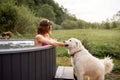 Woman bathing in hot tube, while resting with her dog on nature Royalty Free Stock Photo