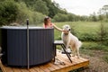 Woman bathing in hot tube, while resting with her dog on nature Royalty Free Stock Photo