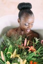 Woman bathing in a tub full of foam. Beautiful african american bride in decorated bath. Beautiful african american