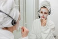 woman in a bathrobe brushes her teeth and looks at herself in the mirror Royalty Free Stock Photo