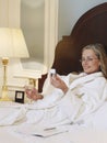 Woman In Bathrobe With Cellphone And Wineglass In Bed Royalty Free Stock Photo