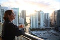 Woman in bathrobe drinking Her morning coffee or tea on a downtown balcony. beautiful sunrise in downtown Miami. Woman enjoying Mi Royalty Free Stock Photo