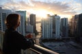 Woman in bathrobe drinking Her morning coffee or tea on a downtown balcony. beautiful sunrise in downtown Miami. Woman enjoying Mi