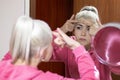 Woman in bathrobe looking at pimple on face into the mirror and try to squeeze it Royalty Free Stock Photo