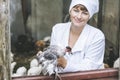 Woman in Bathrobe smiling young veterinarian checks the hens on
