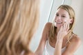 Woman in bathroom applying face cream