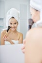 Woman in bathroom applying makeup on