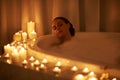 Woman, bathtub and candles for relax treatment at spa or cleaning routine with bubbles for washing, hygiene or wellness