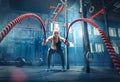 Woman with battle rope battle ropes exercise in the fitness gym.