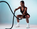 Woman, battle rope or training on blue background in studio for exercise, training or workout for strong arm muscles