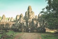 Woman in Bayon Temple looking at stone faces, Angkor Thom, morning light clear blue sky. Buddhism meditation concept, world famous Royalty Free Stock Photo