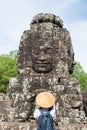 Woman in Bayon Temple looking at stone faces, Angkor Thom, morning light clear blue sky. Buddhism meditation concept, world famous