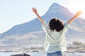 Woman at beach, arms in air and freedom, back view with mountains and travel, praise and sunshine. Female person outdoor