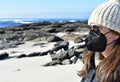 Woman with Covid-19 black face mask on a beach. KN95 or N95 or FFP2 mask.