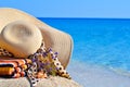 Woman beach hat, bright towel and flowers against blue ocean Royalty Free Stock Photo