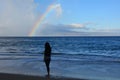 Woman on the beach looking at the rainbow