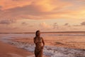 Woman on beach with pink sunset sky over sea on summer vacation Royalty Free Stock Photo