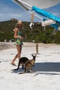 Woman in beach wear and hat orders from beach side kiosk next to kangaroos on the beach beside the surf at Lucky Bay, Cape Le