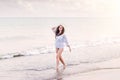 Woman on beach wearing shirt and hat, smiling, holding head Royalty Free Stock Photo