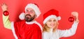 Woman and bearded man in santa hat stand back to back waiting christmas. Couple christmas santa costume hold ornament Royalty Free Stock Photo