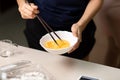 Woman beating eggs with chopsticks closeup