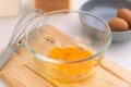 Woman beating eggs in a glass bowl. Young woman cooking in the kitchen