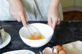 woman beats eggs with a whisk in a white bowl, concept cooking.