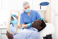 Woman beautician in mask examining face skin of afro american male patient Royalty Free Stock Photo