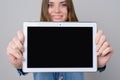 Woman with beautiful face, toothy smile is showing digital tablet with empty black screen. Close up photo, isolated on grey backgr Royalty Free Stock Photo