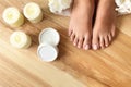 Woman with beautiful feet, candles, flowers and moisturizing cream on wooden floor. Spa treatment Royalty Free Stock Photo